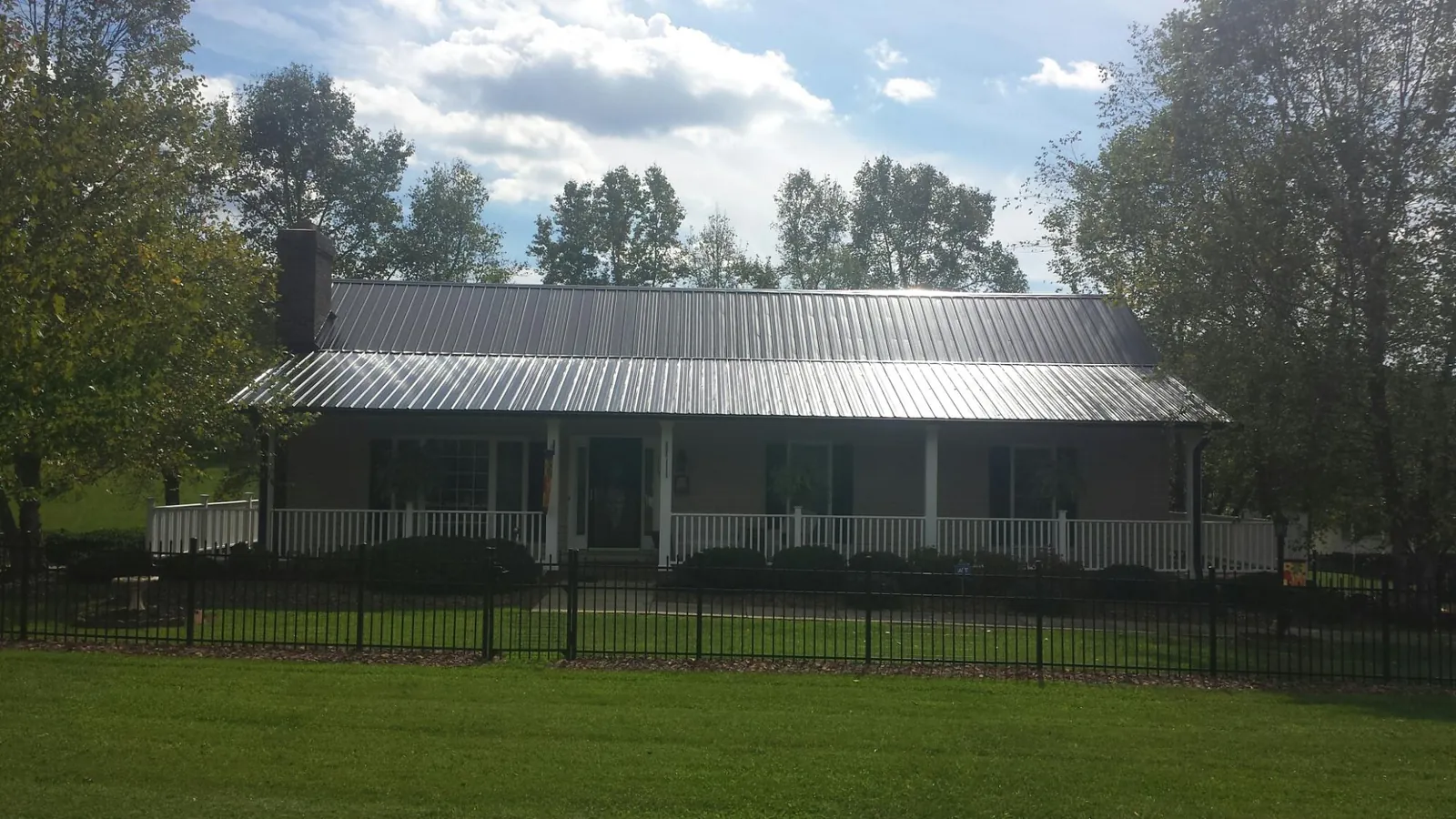 Gray metal roof on a brick ranch with a full width front porch — Gutter Guard Installation work by our crew in Quincy